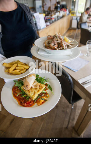 Ristorante interno che serve come cameriera piastre portanti di cibo che serve cibo di servizio servizio pasti di settore Foto Stock