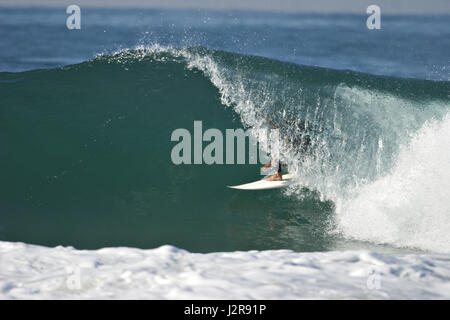 Un maschio surfer cavalca un tubo su un splendido oceano onda. Foto Stock