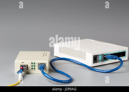 Convertitore di supporti ottici con patch cord e router collegato via cavo in rame Foto Stock