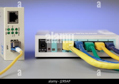 Convertitore di supporti ottici con patch cord e router collegato via cavo in rame Foto Stock