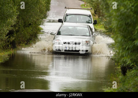 16 Luglio 2012 - i veicoli guida attraverso le inondazioni del Somerset livelli sulla strada tra Glastonbury e Godney Foto Stock