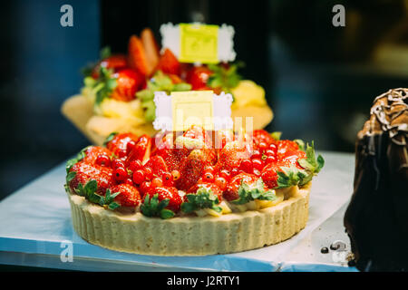 Fresca Torta dolce con ribes e bacche Fragole sulla sommità in una pasticceria Display in vetro Foto Stock
