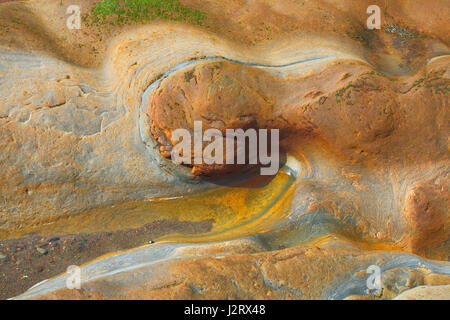 Guardando verso il basso sul ferro-rocce colorate sul terreno a Spittal beach, vicino Berwick-Upon-Tweed, Northumberland. Foto Stock