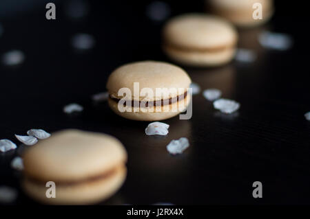 Amaretti con crema di cioccolato ordinati in linea decorato con ciottoli e sabbia Foto Stock