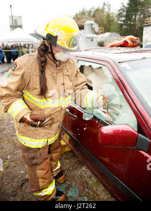 Partecipante fire fighter e Howe Sound studente secondario Kei opere grigio su un veicolo esercizio di estrazione durante il fuoco Junior Academy. Foto Stock