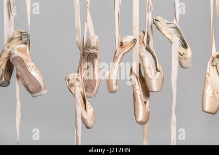 Più appeso beige scarpe da ballo su sfondo grigio in studio. Primo piano. Orizzontale. Foto Stock