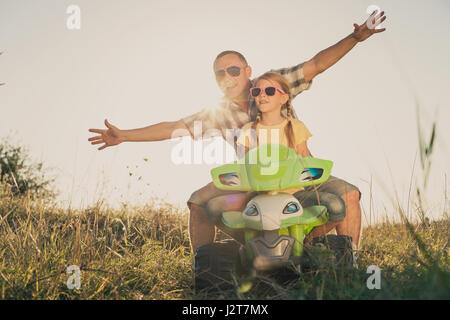 Padre e figlia giocando sulla strada al giorno. Essi guida su quad bike nel parco. Le persone aventi il divertimento sulla natura. Concetto di cordiale f Foto Stock