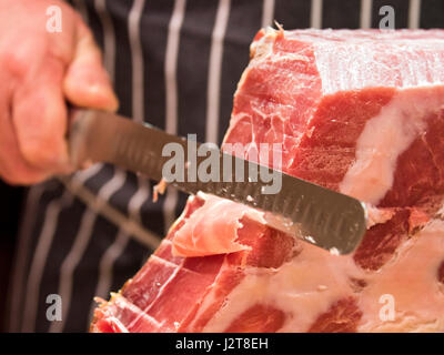 Chiudere orizzontale di un macellaio di tranciatura di un prosciutto Serrano. Foto Stock