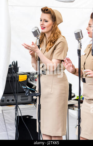 Saluto alla 40s rievocazione giorno. Il cantante da Knightingales, un trio di donne un gruppo di canto in WAAF uniformi, sul palco di eseguire la guerra mondiale due canzoni Foto Stock