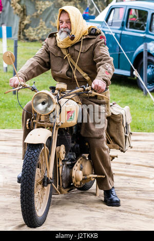 Inghilterra, sandwich. Saluto alla 40s evento. Uomo maturo dal deserto di ratto Storia Vivente gruppo attorno a cavalcare off su un motore vintage-ciclo. Il fumo di una tubazione. Foto Stock