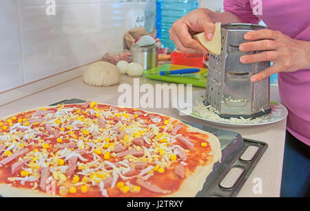 Donna preparare la pizza in cucina Foto Stock