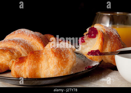 Vista laterale di cornetti freschi su un tavolo per la colazione impostazione Foto Stock