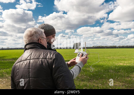 Due uomini giocando con il drone in corrispondenza del campo verde Foto Stock