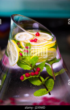 Una bevanda rinfrescante al limone, mirtillo, lampone e menta in un grande recipiente di vetro con Tagliare diagonalmente top Foto Stock