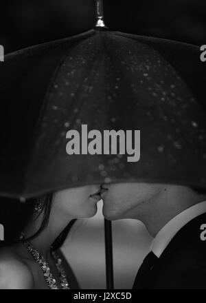 Silhouette di baciare giovane sotto l'ombrello. Immagine in bianco e nero Foto Stock