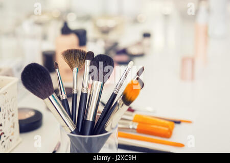 Set di professionale di pennelli per il trucco in vetro sulla tavola closeup. Filtra foto con messa a fuoco selettiva e tonificante. Make-up table nel salone di bellezza. Ancora lif Foto Stock