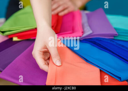 La scelta di un colore di tessili. I campioni di tessuto colorato nelle mani della donna. Vista ingrandita di femmine della mano che tiene il tessuto dei campioni di colore Foto Stock