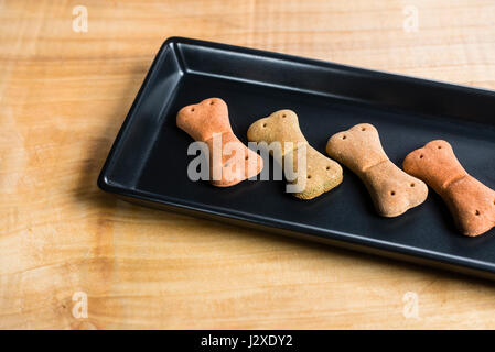 Cibo per cani in un piatto nero rettangolare su una tavola di legno servito in modo molto chic. Foto Stock