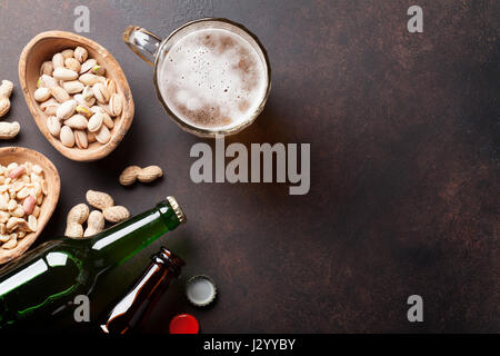 La birra lager e snack sulla tavola di pietra. Vari dadi. Vista da sopra con lo spazio di copia Foto Stock
