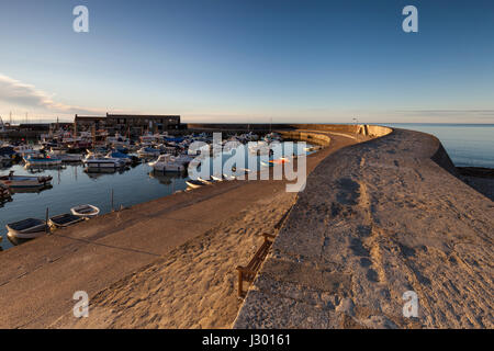 Vista dalla Cobb di Lyme Regis, Dorset su Jurassic Coast su una mattina di sole con cielo blu. È inoltre possibile vedere le barche nel porto. Foto Stock