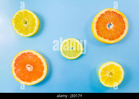Due pompelmo e tre fette di limone su sfondo blu. Immagine minimalista di stile con qualche copia spazio per il testo Foto Stock