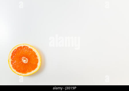 Vista superiore della singola fetta di pompelmo su sfondo bianco. Immagine minimalista di stile con copia spazio per il testo Foto Stock