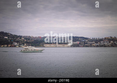 Vista del Bosforo e di una barca privata. Barca passando dal bellissimo edificio sul lato Asiatico di Istanbul, Turchia su un nuvoloso giorno di primavera. Foto Stock