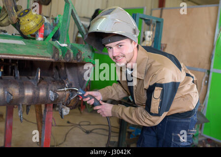 Felice apprendista saldatore a lavorare nell'impianto Foto Stock