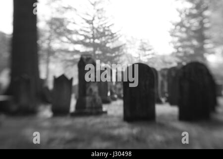 Vecchie lapidi sfocate sono visti in un cimitero. Foto Stock