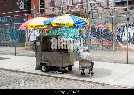 Un uomo in un musulmano taqiyah cap in esecuzione di un alimento in stallo sulla strada di SoHo a New York City Foto Stock