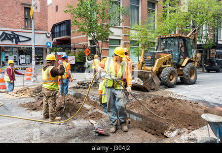 Un gruppo di lavoratori edili riparare le infrastrutture della metropolitana su una strada di Soho a New York. Uomo in primo piano può contenere un tubo aria compressa. Foto Stock