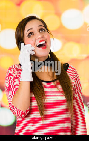 Closeup ritratto della cute giovane ragazza clown mime tramite telefono cellulare Foto Stock