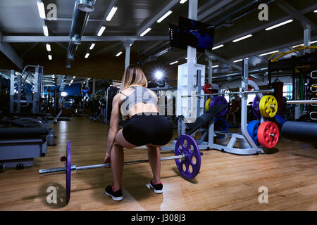 Una ragazza sportiva è fare gli esercizi in palestra con barbell Foto Stock