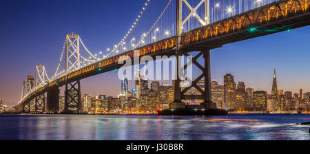 Classic vista panoramica del famoso Oakland Bay Bridge con lo skyline di San Francisco illuminata nella splendida post tramonto crepuscolo, CALIFORNIA, STATI UNITI D'AMERICA Foto Stock