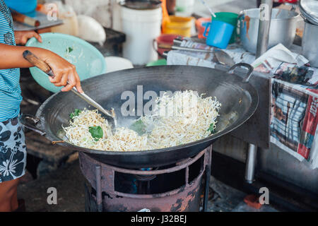 GEORGE TOWN, Malesia - 23 Marzo: Donna cuochi stir-noodles fritti con i germogli di soia presso Kimberly cibo di strada del mercato notturno su Marzo 23, 2016 in George a Foto Stock