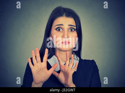 Spaventata donna sollevando in alto le mani hanno paura di essere attaccato evitando spiacevoli situazione isolata su sfondo grigio Foto Stock