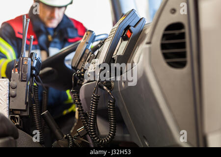 Firefighter aziona un veicolo di emergenza con la comunicazione vista interna e cazzuola Foto Stock