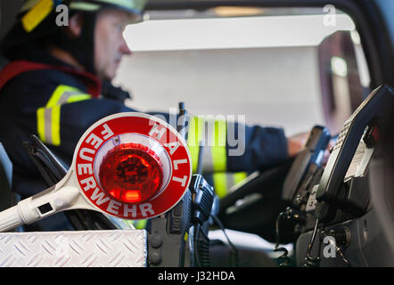 Firefighter aziona un veicolo di emergenza con la comunicazione vista interna e cazzuola Foto Stock