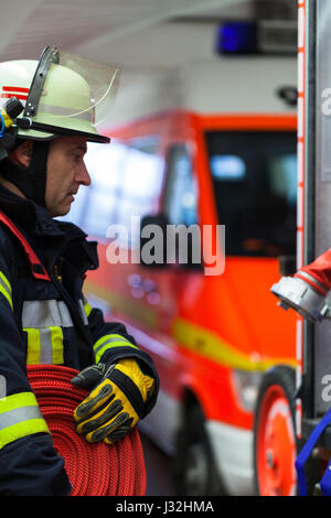 Vigile del fuoco tedesco nella stazione dei vigili del fuoco con un tubo flessibile di acqua in mano Foto Stock