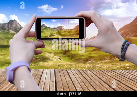 Una donna è di fotografare un paesaggio bello della montagna su un telefono cellulare. Foto Stock