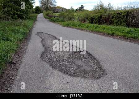 Una pentola di grandi dimensioni foro su una strada di campagna in Inghilterra. Foto Stock