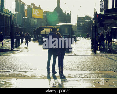 Coppia giovane stile urbano silhouette tanga alla moda di Glasgow a piedi tenendo le mani insieme Foto Stock