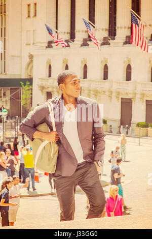 Giovane americano africano uomo che viaggia in New York, trasporto borsa a tracolla, a piedi fino a passi, in piedi di fronte a vintage edificio per uffici, cercando Foto Stock