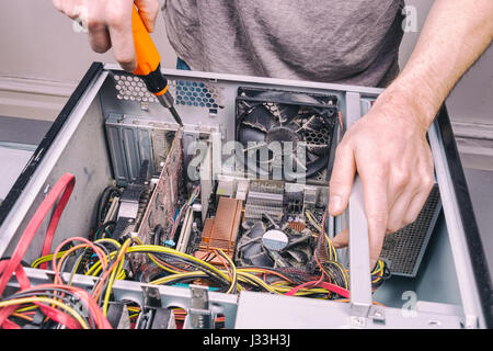 Uomo che fissa un vecchio computer desktop utilizzando un cacciavite Foto Stock