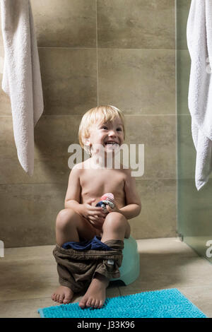 Un bambino di 2 anni ragazzo si siede sul vasino Foto Stock