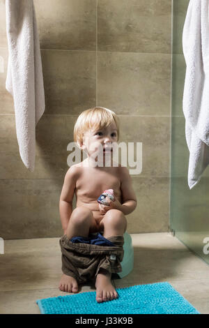 Un bambino di 2 anni ragazzo si siede sul vasino Foto Stock