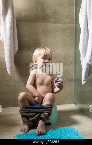 Un bambino di 2 anni ragazzo si siede sul vasino Foto Stock