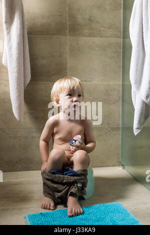 Un bambino di 2 anni ragazzo si siede sul vasino Foto Stock