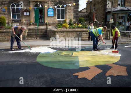Tre persone pulire un grande anatra stampato sulla strada Addingham, Yorkshire. U.K. in preparazione per il Tour de Yorkshire cycle race. Foto Stock