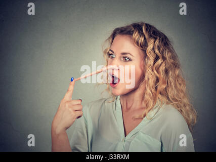 Donna con il naso lungo isolato sul muro grigio Sfondo. Concetto bugiardo. Volto umano espressioni, emozioni, sentimenti. Foto Stock